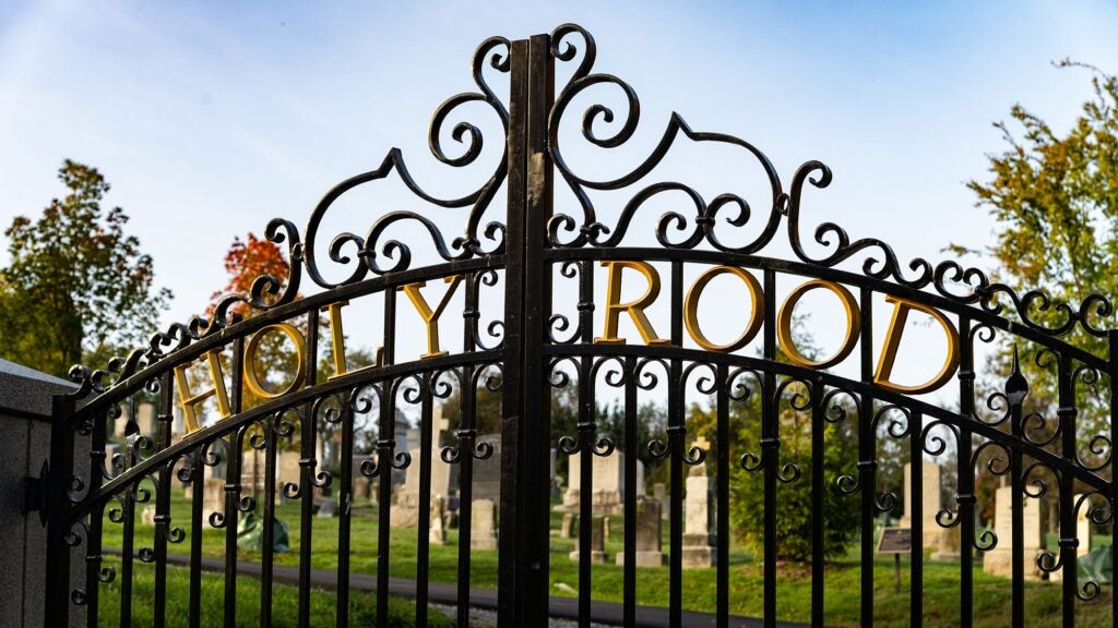 Holy Rood Cemetery's iron gate with tombstones in the background.
